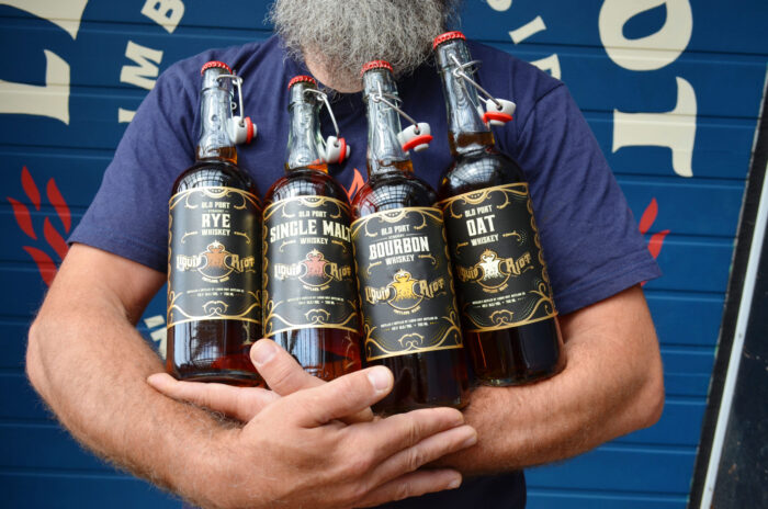 Head Distiller holding all four whiskey bottles